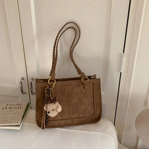 Detalle del bolso tote de gamuza retro con correa trenzada y anillo de metal dorado