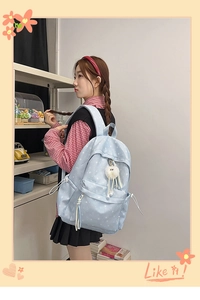 Détail du sac à dos bleu clair avec imprimés d'étoiles et un joli pompon blanc en peluche