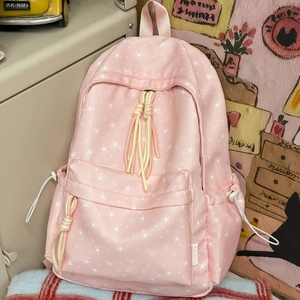 Détail du sac à dos en toile rose avec imprimé étoiles blanches et pompons