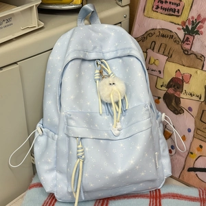 Détail d'un sac à dos bleu clair avec imprimés étoiles et charmant pompon en peluche