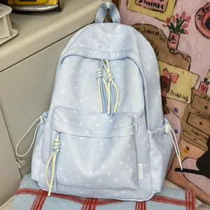 Détail du sac à dos bleu clair avec motif d'étoiles blanches et cordons à glands élégants