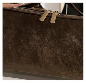 Detail der dunkelbraunen Wildleder-Kosmetiktasche mit goldenem Doppelreißverschluss