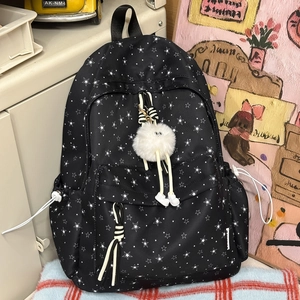 Détail d'un sac à dos en nylon noir à motif d'étoiles avec un pendentif peluche