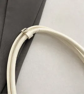 Dettaglio della tracolla cilindrica in pelle bianco sporco con fibbia in metallo dorato