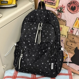 Gros plan d'un sac à dos noir à motifs d'étoiles blanches avec poche latérale à cordon