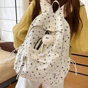 Détail d'un sac à dos en toile blanche avec étoiles noires et pendentif monstre en peluche
