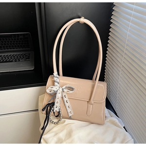 Detalle de bolso de hombro beige brillante con lazo de encaje y colgante de perlas