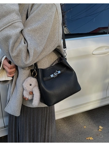 Detalle del bolso de cubo en cuero granulado negro con cierre plateado y colgante de conejo