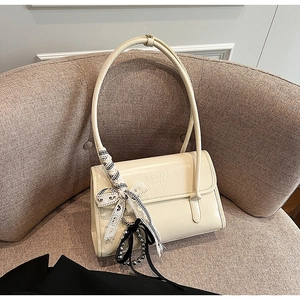 Detalle del bolso de cuero blanco crema con texto en relieve y lazo de encaje