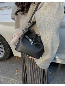 Detalle de bolso cubo de piel negra con herrajes plateados y colgante de peluche suave