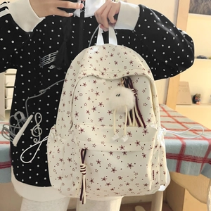 Détail du sac à dos fleuri avec pompon et glands décoratifs dans un cadre intérieur