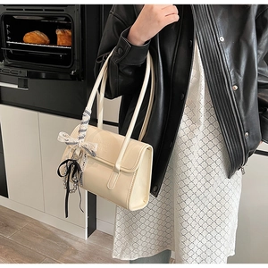 Detalle de un bolso de hombro chic en cuero crema con lazo y colgante de cuentas