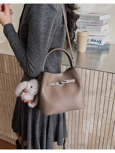 Detalle de bolso bucket de cuero marrón con cierre plateado y adorno de conejo de peluche suave