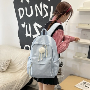 Détail du sac à dos bleu clair à motifs d'étoiles avec un pompon en peluche doux