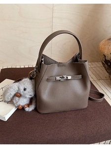 Detalle del bolso cubo de cuero marrón oscuro con asa y un adorable colgante de conejo