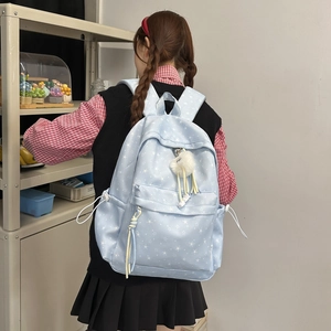 Détail du sac à dos bleu clair pour l'école avec motifs étoiles et pendentif boule en peluche