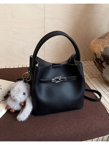 Detalle del bolso tipo cubo en cuero granulado negro con cierre y colgante de conejo de peluche