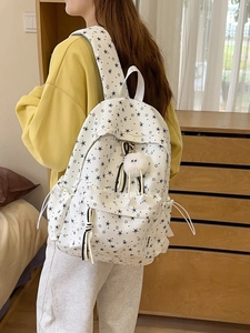 Sac à dos blanc avec imprimé étoiles et pompon mignon montré dans un décor de chambre