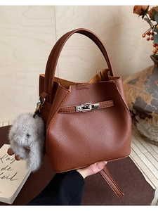 Detalle del cuero marrón granulado y la hebilla metálica en el bolso estilo cubo