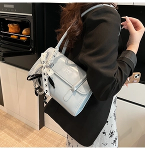 Detalle del bolso de hombro azul claro con lazo de encaje y cuentas metálicas de moda
