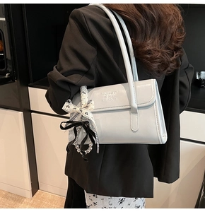Detalle del bolso de hombro en cuero brillante azul claro con cinta de lazo y cuentas