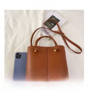 Braune Lederhandtasche mit Metallschnalle und Smartphone zum Größenvergleich