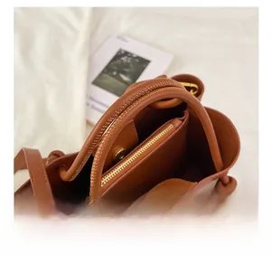 Detailansicht der Innenausstattung einer braunen Leder-Eimertasche mit goldenen Verschlüssen
