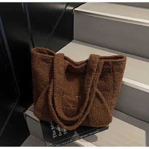Detail of plush brown tote bag with bear embroidery on a modern minimalist staircase