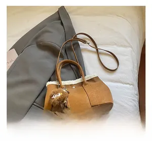 Détail sac seau en cuir marron avec bordure en fausse fourrure blanche et charm
