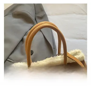 Détail d'un sac seau en daim marron avec bordure en laine de mouton blanche et boucles