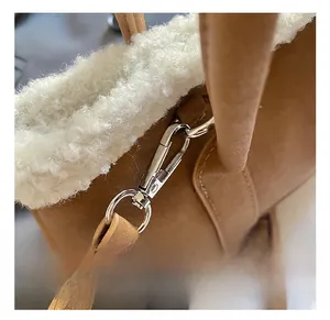 Détail du fermoir en métal argenté sur un sac seau en daim marron avec bord en fausse fourrure