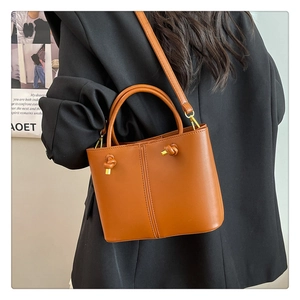 Braune Eimer-Tasche aus Leder kombiniert mit einem schwarzen Blazer für Damen
