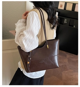 Detail of vintage brown leather tote bag with beaded tassel and fashion text logo