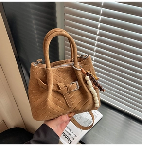 Dettaglio della borsa a secchiello in pelle scamosciata marrone con texture a V