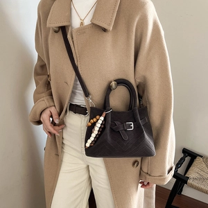 Dettaglio borsa a secchiello vintage in pelle scamosciata marrone con decoro di perline