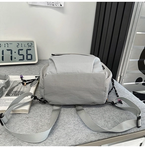 Detail showing the gray textured fabric and side woven label of a minimalist urban backpack