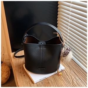 Detailed view of black bucket bag with lychee grain leather and leopard bow pompom charm