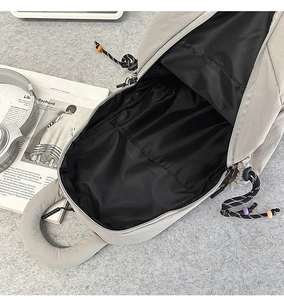 Detail view of nylon crossbody bag interior with black lining and colorful zipper pulls