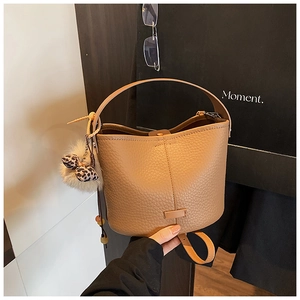 Detail of caramel bucket bag in lychee leather with leopard bow and plush charm