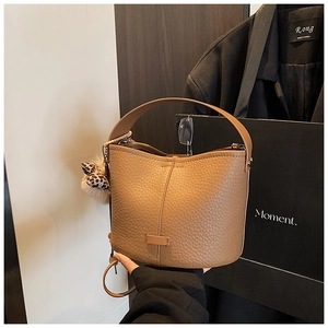 Close-up of camel brown bucket bag with lychee texture and leopard print pompom