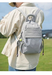 Detail of light gray nylon backpack with grid pattern and tennis ball keychain