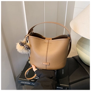 Detail of brown pebbled leather bucket bag with fur pom-pom and leopard print bow