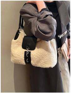 Detail of plush tote bag showing beige faux fur texture and black leather handle contrast