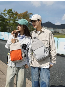 Dual models wearing lightweight nylon backpacks in orange contrast and minimalist grey