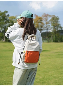 Outdoor shot showing details of the color-block backpack with orange and white panels