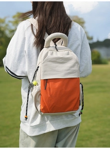 Detail view of cream canvas backpack with orange checkered fabric and tennis racket charm