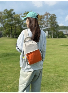 Close-up of lightweight nylon backpack in grey and orange patchwork design for outdoor wear