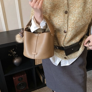 Detail view of camel leather bucket bag with leopard print charm on female model