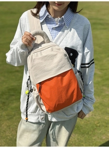 Detail of beige and orange mesh backpack featuring durable handle and tennis ball charm