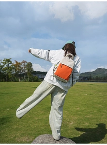 Outdoor view of lightweight cream and orange backpack worn by a model in nature